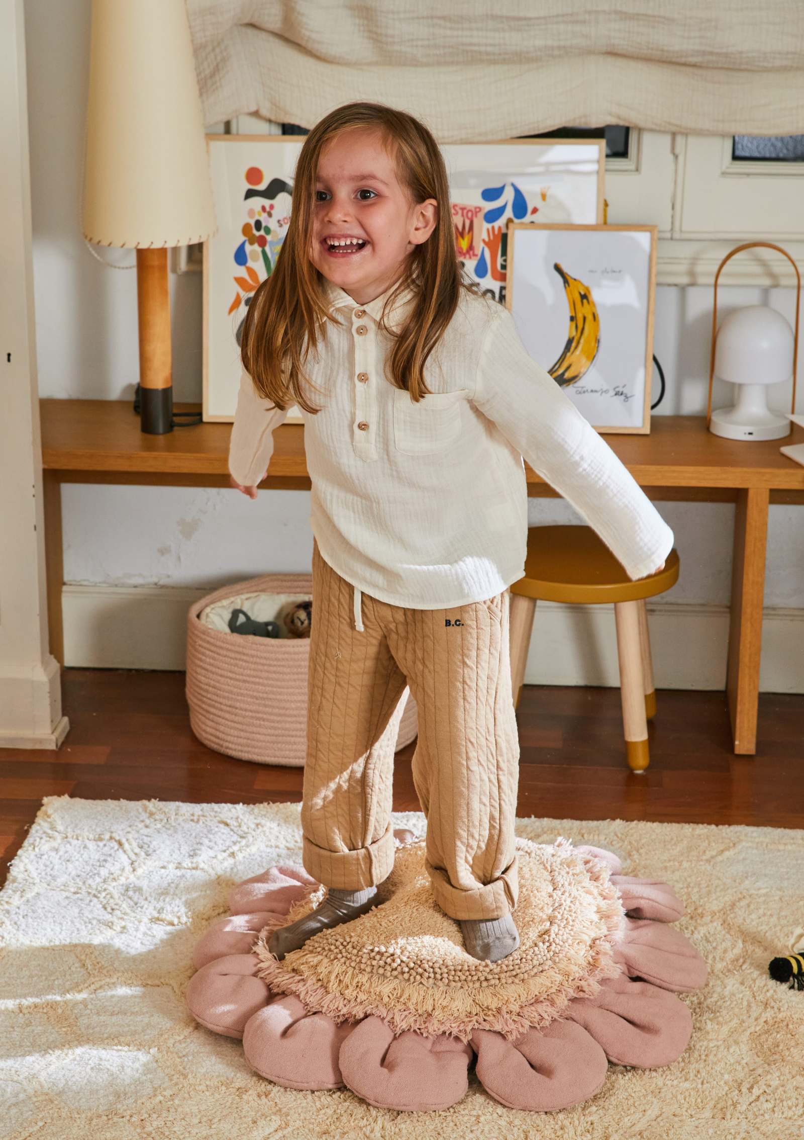 Mädchen steht auf Lorena Canals Bodenkissen 'Pink Daisy'