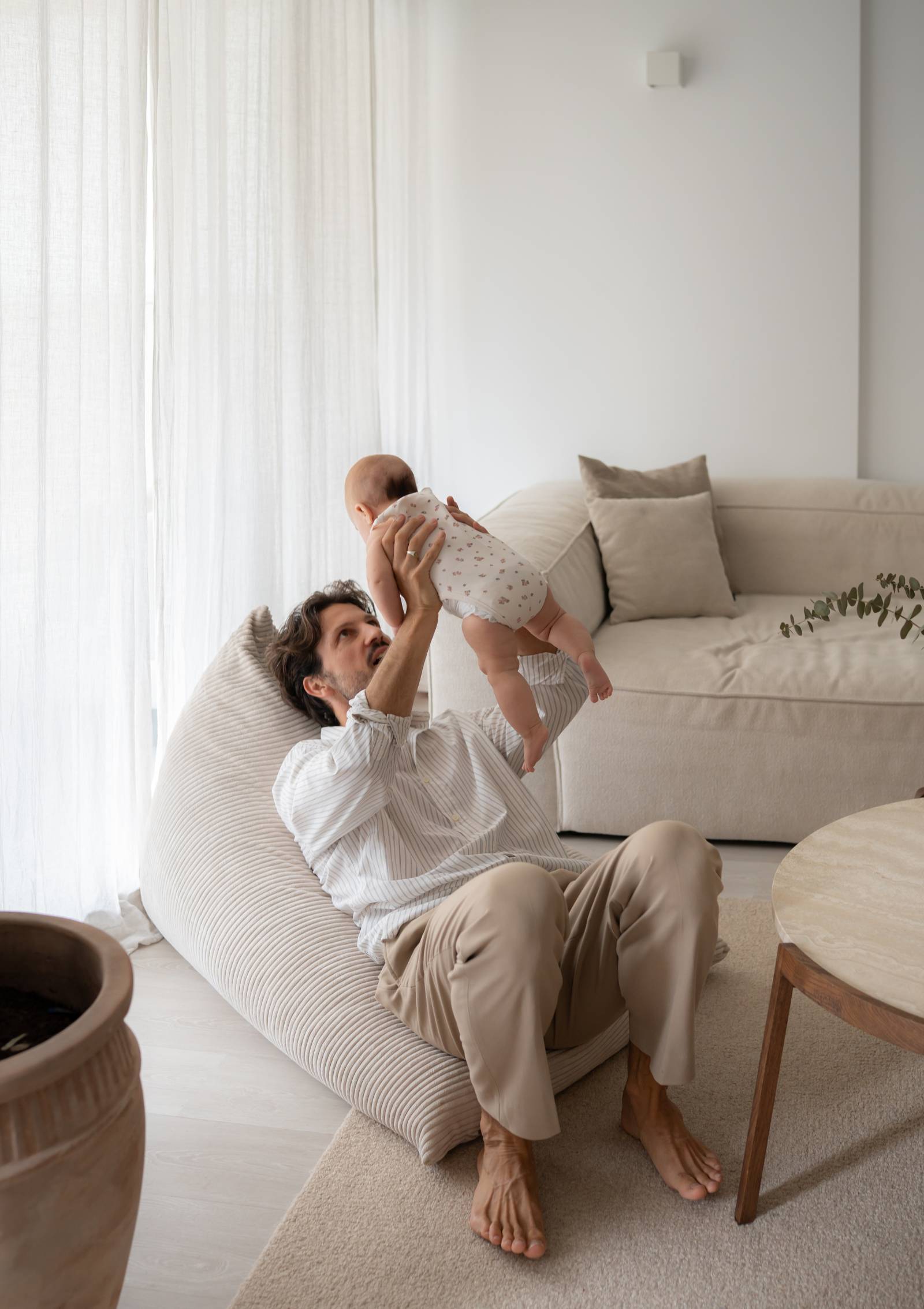 Mann mit Baby liegt im Funzy Lounger Sitzsack Cord Creme Beige