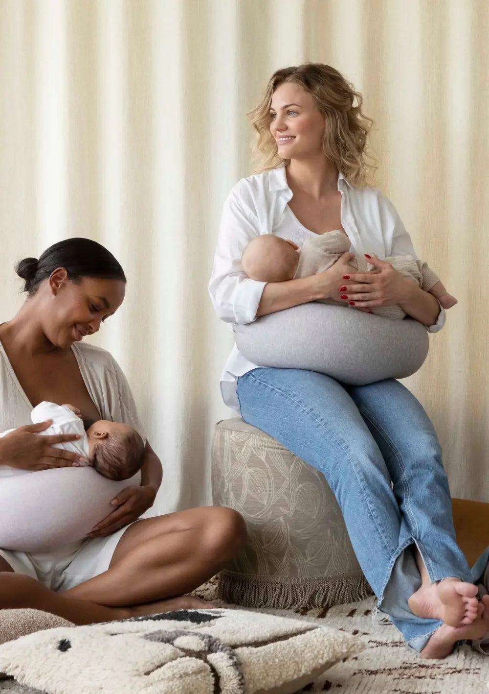 Zwei Mütter sitzen zusammen und stillen ihre Babys – mit dem bbhugme Stillkissen als Unterstützung, in einem hellen, gemütlichen Raum.