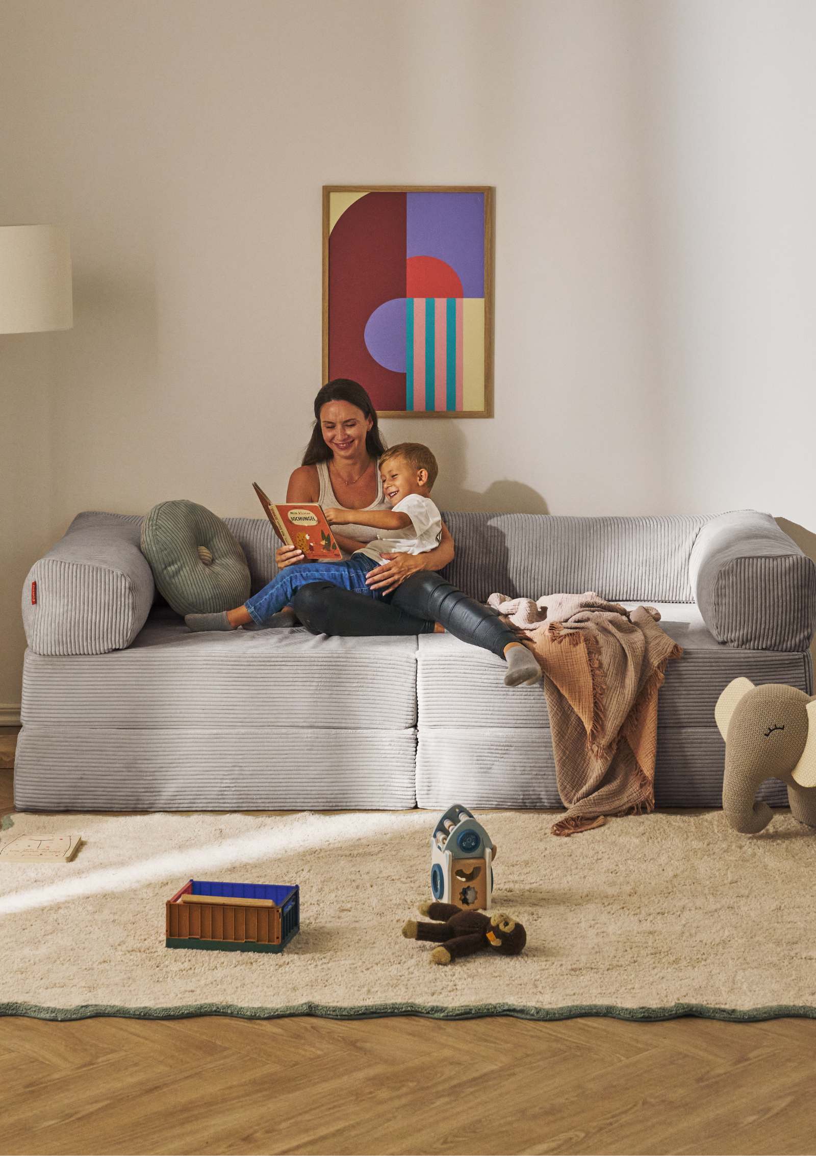 Mutter und Kind beim Lesen auf dem Funzy Family Sofa Cord Koala Grau