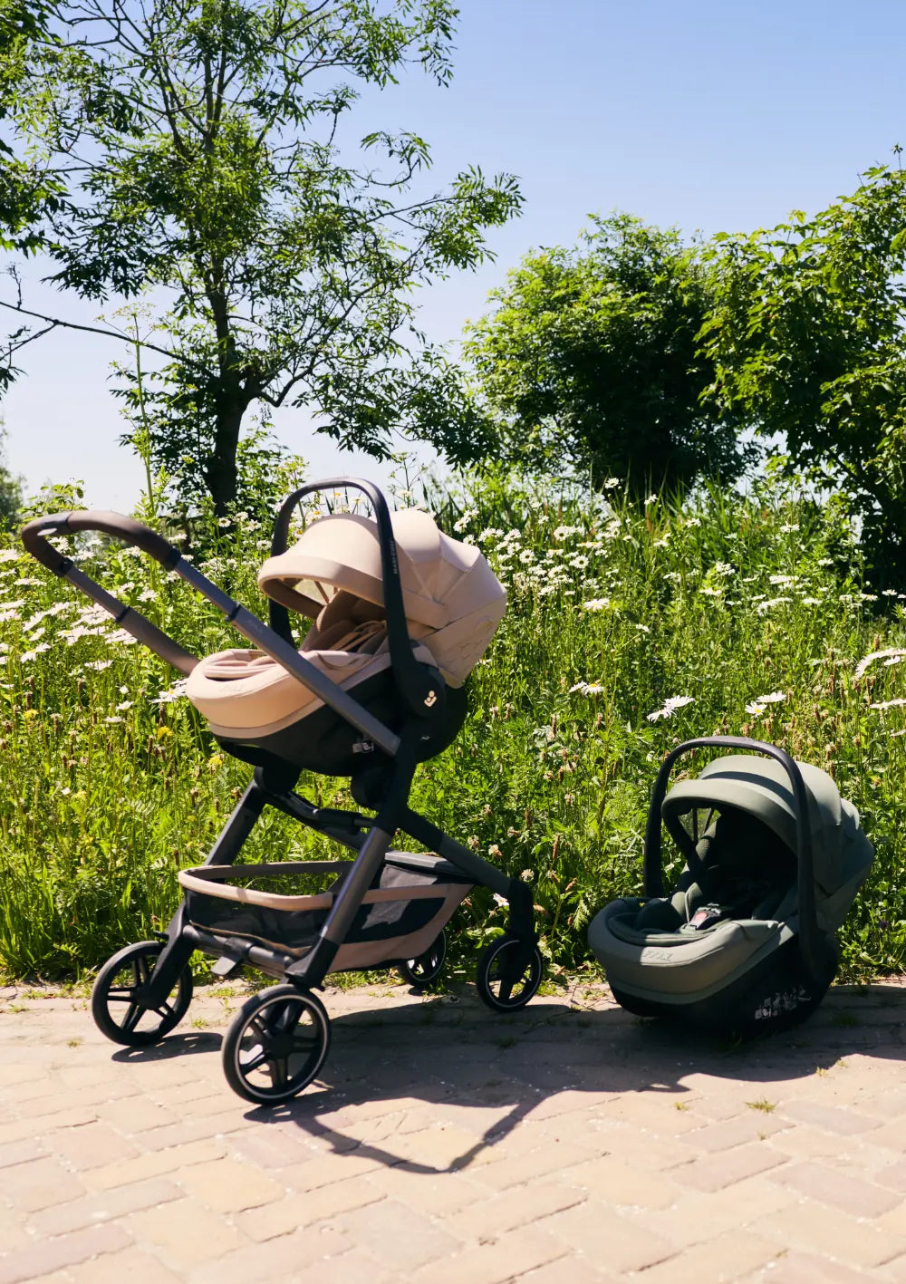 Joolz x Maxi-Cosi Babyschale 'Pebble Slide Pro' Sandy Taupe befestigt an einem Joolz Kinderwagengestell, daneben die Joolz x Maxi-Cosi Babyschale 'Pebble Slide Pro' Forest Green