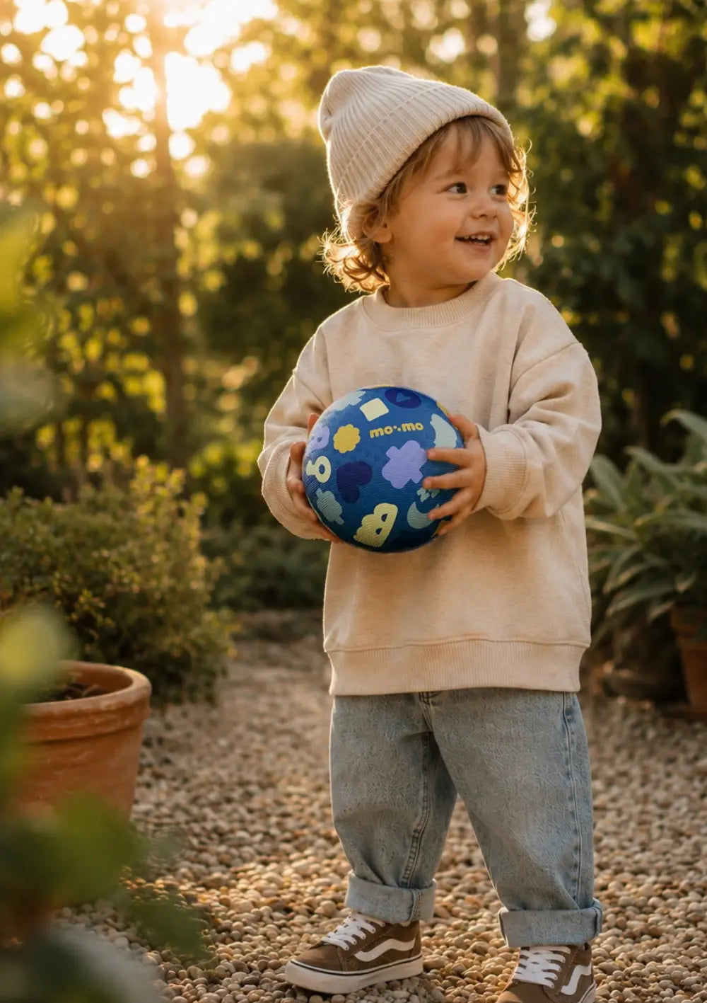 Junge spielt draußen mit dem Ball aus dem mo:mo Starter-Set 'Bouncing Buddy' Spielball mit App-Zugang Aqua