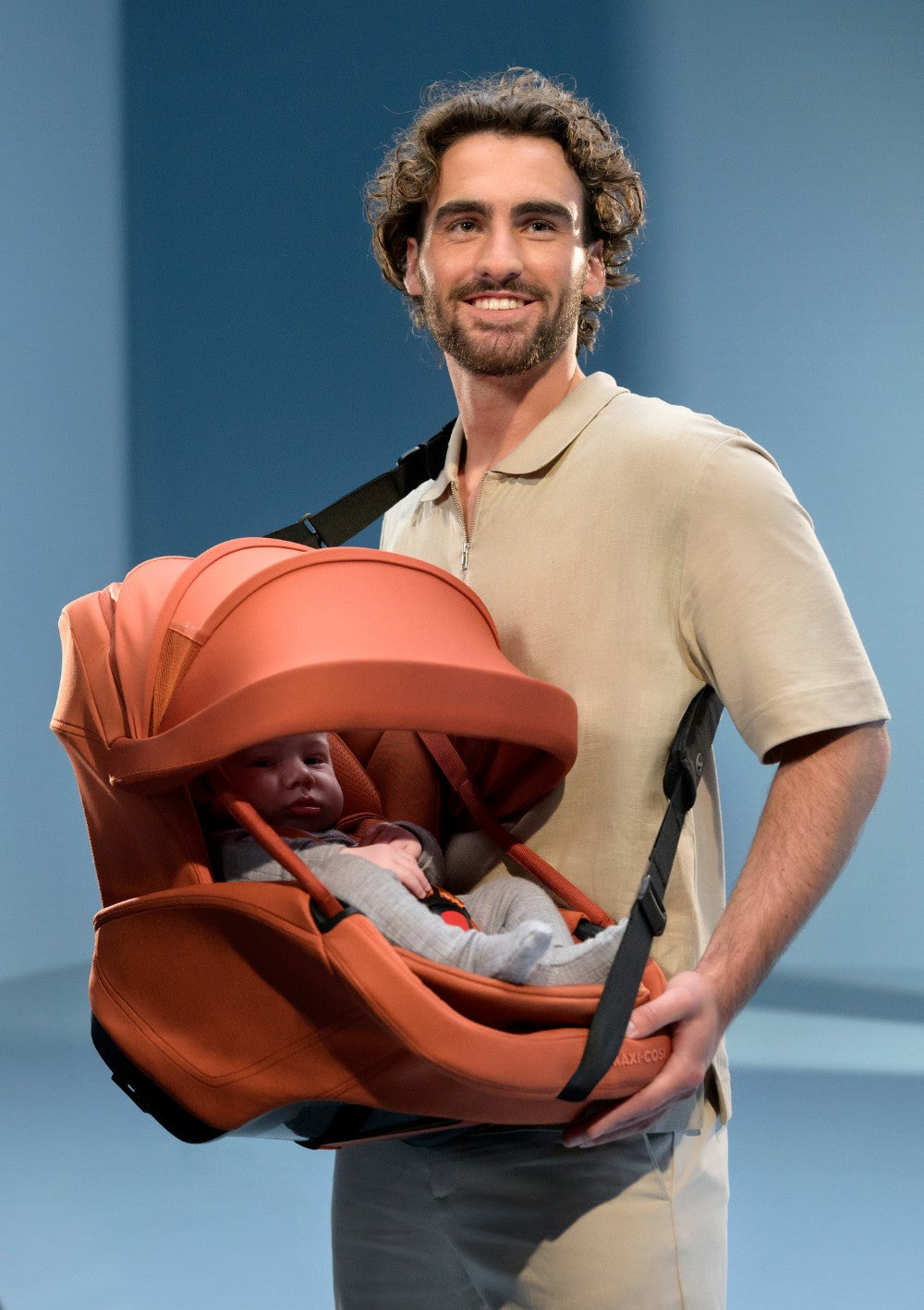 Mann trägt  Maxi-Cosi Babyschale 'Coral Slide Pro' Copper Terra mit Tragegurt
