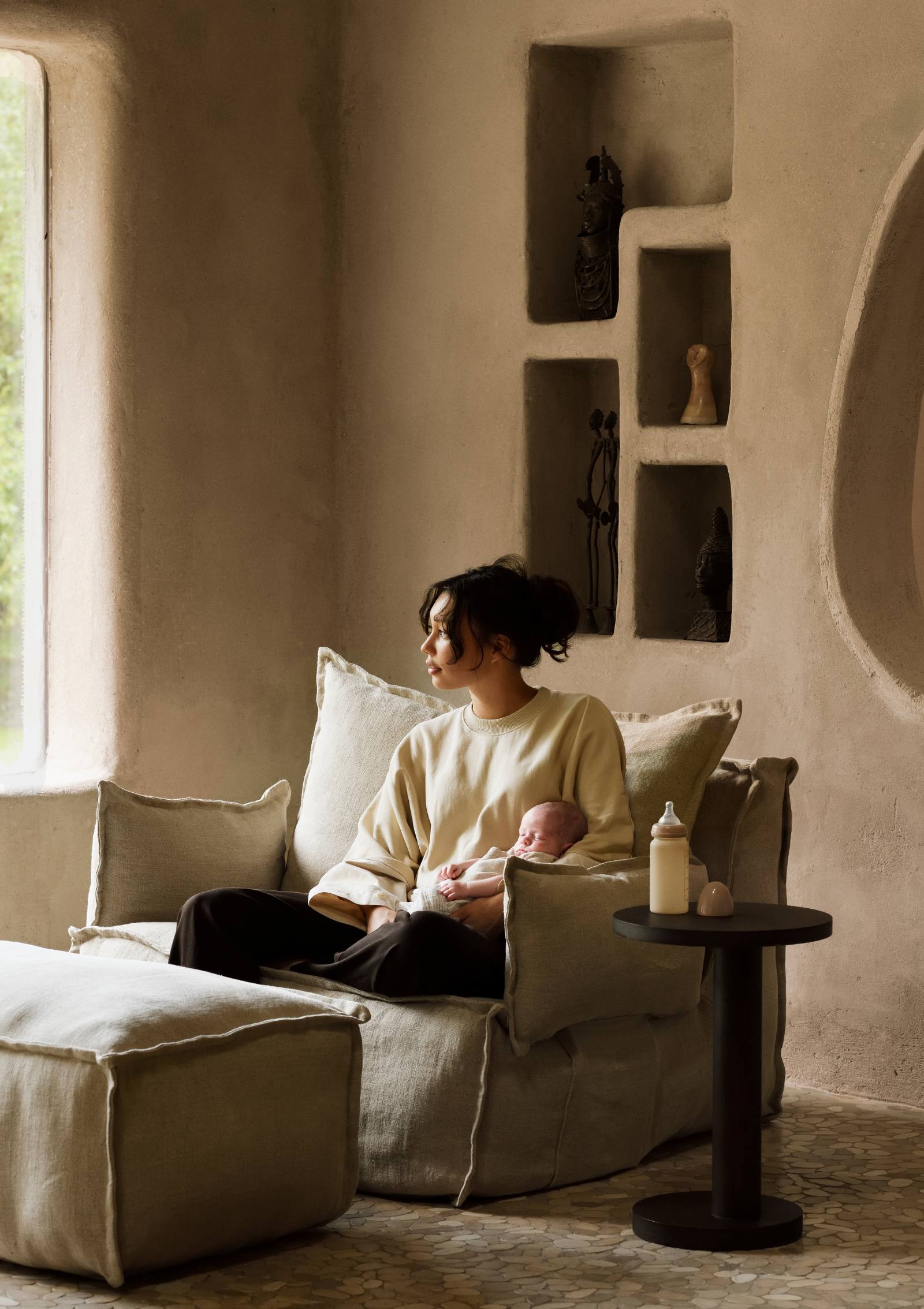 Frau hält Baby im Arm, im Quax Lounge-Sessel 'Linen Lounger' Beige mit zwei Armlehnen sitzend