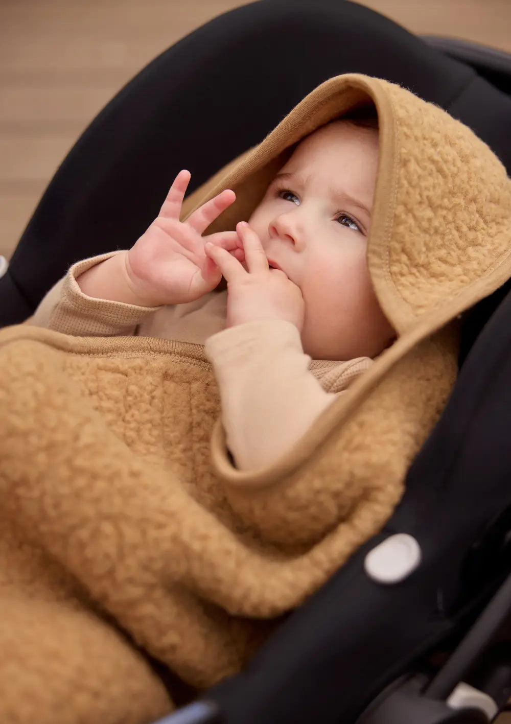 Baby mit der Jollein Merino Einschlagdecke 'Sherpa' Dark Hazel in einer Babyschale