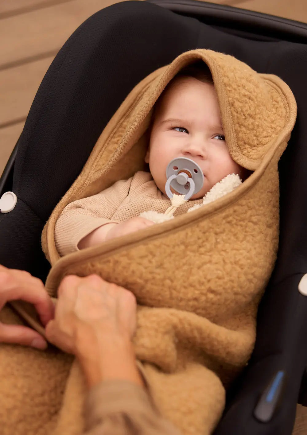 Baby mit Schnuller, eingekuschelt in der Jollein Merino Einschlagdecke für Babyschale 'Sherpa' Dark Hazel
