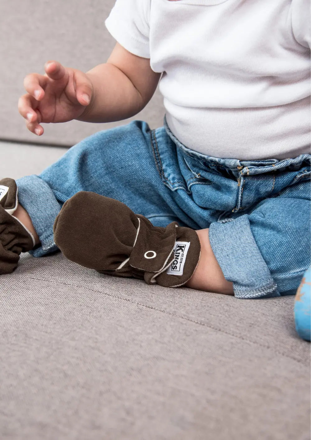 Sitzendes Baby mit Jeans und Kings & Rebels Booties Gamuza Chocolate
