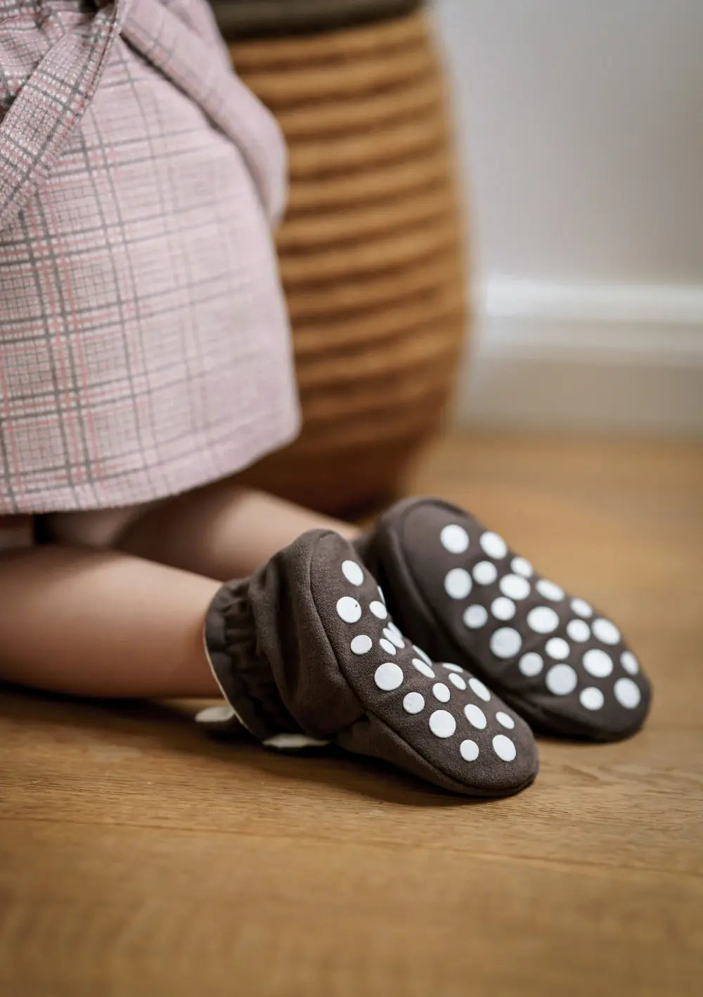 Mädchen kniet auf einem Holzboden und man sieht die Schuhsohle mit Antirutschnoppen der Kings & Rebels Booties Gamuza Chocolate